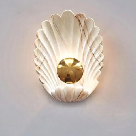Sur un fond blanc on voit une applique murale en forme de coquillage blanche et dorée.