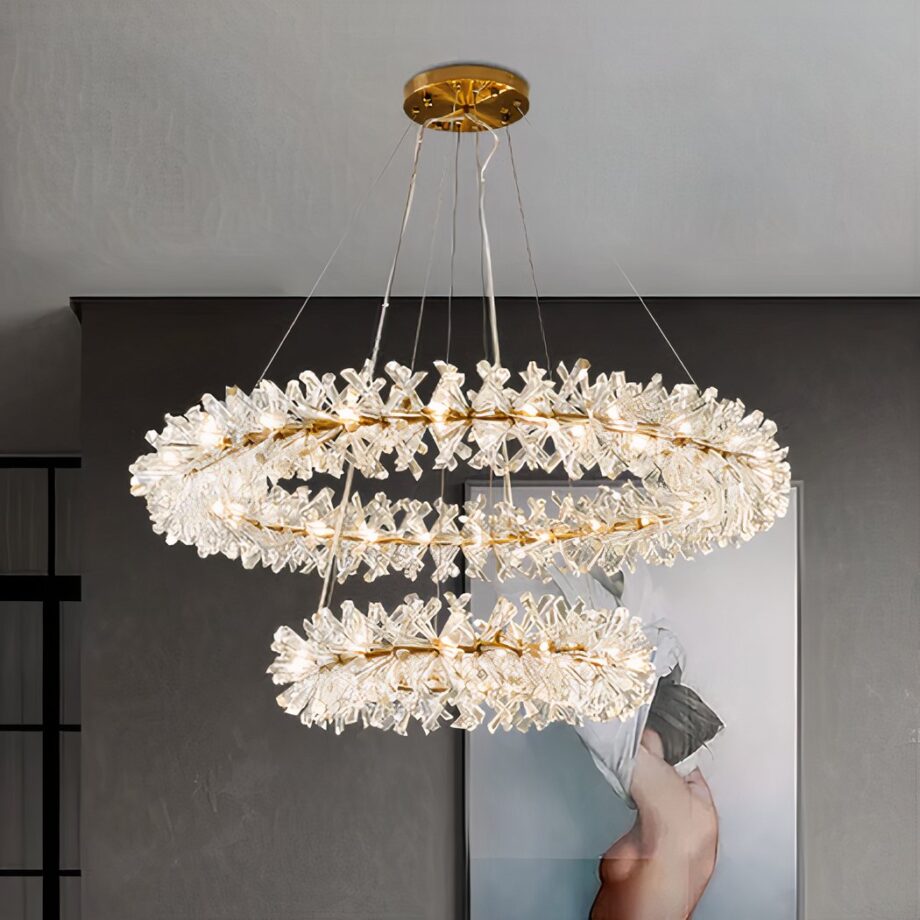 Lampadario a corona di cristallo a due livelli, acceso sopra una cassettiera con specchio