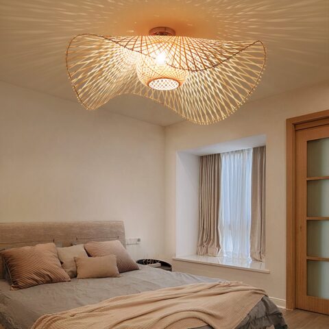 Lampadario chambre adulte de style bohème en rotin allumé sur fond beige avec un lit