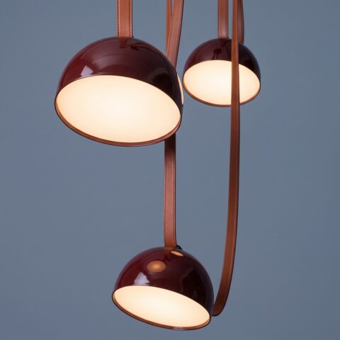 Lampada a sospensione a tre teste, cupole laccate bordeaux e cinghie effetto cuoio cognac