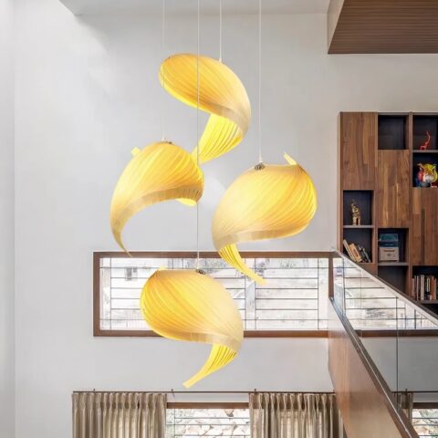 Quatre lustres suspendus, aux formes très aériennes et originales. Dans le fond on voit un grand mur blanc, une fenêtre horizontale, sur le côté droit une balustrade en verre et un morceau de bibliothèque.