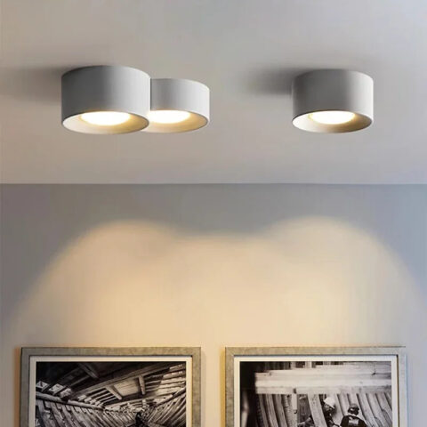 Lampadario moderne LED au design minimaliste de cylindre et spot encastré en version blanche, fixé au plafond et allumé, dans un salon.