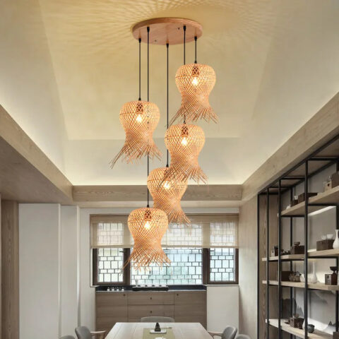 Lampadario style chapeau de paille tissé à la main accroché au plafond et allumé, au-dessus d'une table de salle à manger.