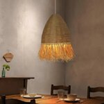 Lampadario en paille et corde fait à la main suspendu et allumé au-dessus d'une table de salle à manger dressée pour le repas.