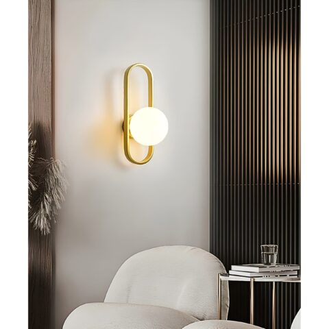 on voit dan sun salon avec un fauteuil blanc une applique murale moderne dorée avec une boule